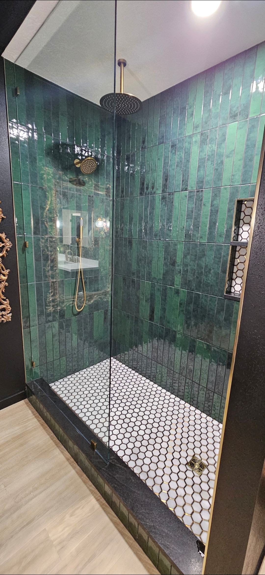 Custom green-tile shower with glass enclosure and brass fixtures.